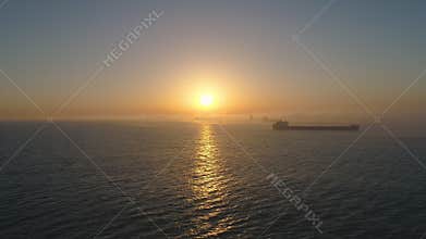 Cargo ship sailing on open sea water and beautiful sunrise  aerial drone video 4K