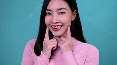 Smiling Asian woman wearing orthodontic retainer on blue screen background. Dental care and teeth