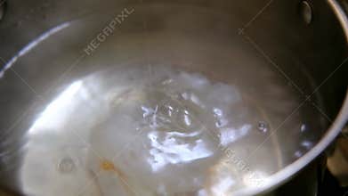 Cooking poached eggs. Dip a raw egg into boiling water
