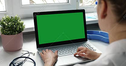 doctor typing on her laptop computer in medical clinic office. green screen. slider shot