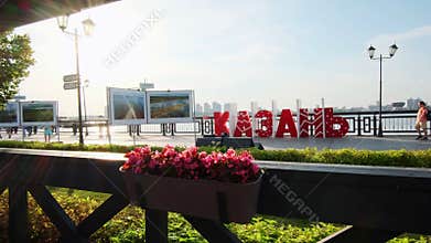 People walk past word Kazan installed on city embankment