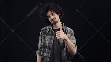 Cheerful charismatic young man, looks like hands smiling at the room. Hipster in a plaid shirt and black T-shirt