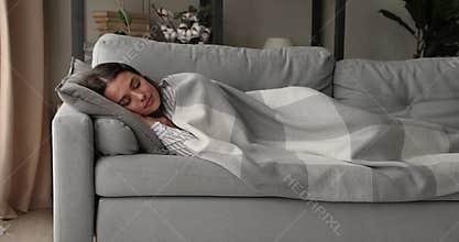 Young woman lying on sofa enjoy comfort sleep under plaid