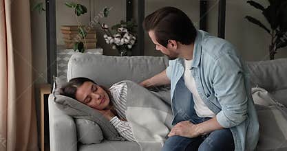 Caring husband cover sleeping beautiful wife with cozy plaid