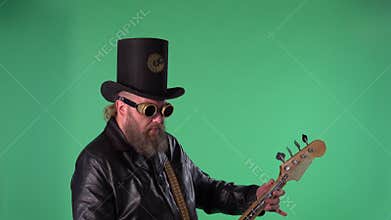 Bearded man in long leather coat, an Irish style hat and original glasses plays the red guitar. Rock musician plays bass