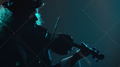 Violinist musician plays a musical instrument. Silhouette of a man in a black suit and an Irish hat, playing a melody on