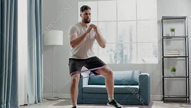 Active sportsman steps in half squat with elastic belt