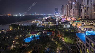 Aerial view of beach and tourists walking in JBR with skyscrapers night timelapse in Dubai, UAE