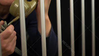 Prisoner in jail cell making a telephone call
