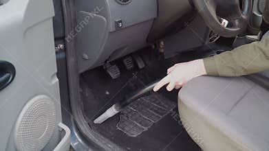 Auto detailing. Vacuum the floor near the pedals with a vacuum cleaner with a nozzle for cleaning holes. A man in work