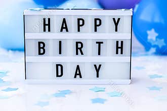 Lightbox with text HAPPY BIRTHDAY on Abstract defocused blurred festive background for holiday. Blue ballons and confetti.