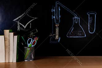 Science Lab set up and Square Academic cap drawn by colored chalk with books, pen stand, and Stationary items placed on a table