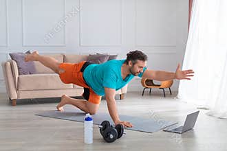 Middle aged man during online Pilates workout at home. Balance exercise. Healthy lifestyle concept.