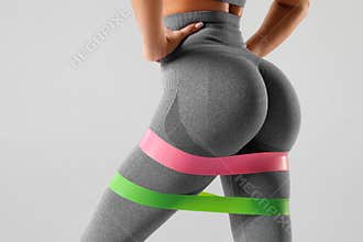 Athletic girl doing exercise for glutes with resistance band. Beautiful butt, fitness woman working out