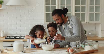 Young biracial father making pancakes with kids at home.