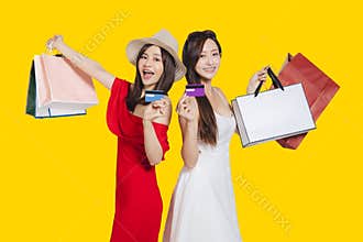 Happy young women dressed in summer clothes holding shopping bags and credit cards
