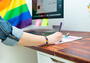 Cultura LGBTQIA. Woman working in office with LGBT accessories