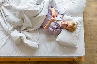 Young woman in bed with tablet pc or smartphone. Social networks addiction concept.