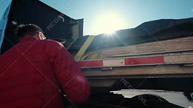 Cargo shipping. Men workers fasten the load on the truck. Close up
