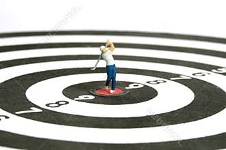 Miniature people toy figure photography. A men golfer doing golf drive swing at center of the dartboard, isolated on white