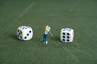Miniature people toy figure photography. Gambling play concept. A men golfer standing in the middle of two dice