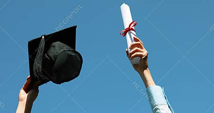 Graduate with diploma and cap in hands against blue sky celebrating college graduation