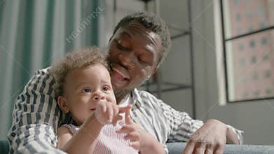 Black father watches TV with toddler daughter and counts
