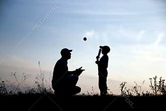 Silhouette of father and son playing baseball on nature family sport