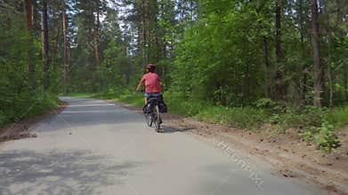 Two young men with backpacks ride bicycles along the road.