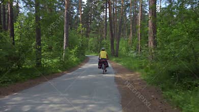 Two young men with backpacks ride bicycles along the road.