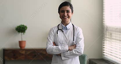 Smiling Indian professional doctor wear coat pose in clinic office