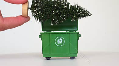 Responsible Disposal: Hand Placing Artificial Christmas Tree in Green Bin