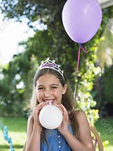 Happy Girl In Tiara Blowing Balloons Outdoors