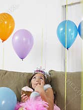Girl Looking Up At Balloons On Sofa