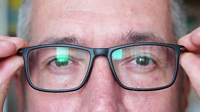 A man puts on glasses with black plastic frames to see better