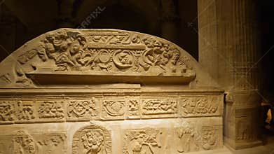 Roman sarcophagus with detailed carvings, captured as the camera zooms out under bounce light, revealing the artifact