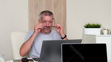 A man working on a laptop puts on glasses to see better