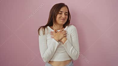 Young blonde woman standing with hands on chest in a grateful gesture, smiling with closed eyes over isolated pink background for