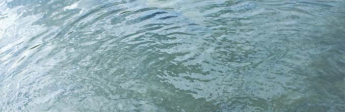 Reflection on light water surface of a lake. Water surface in detail with ripples from the wind.