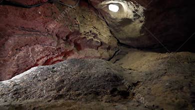 Video of the view from an underground stone cave, from which the exit from the cave is visible.
