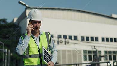 Portrait of man engineer in helmet talking on phone walking along construction site.