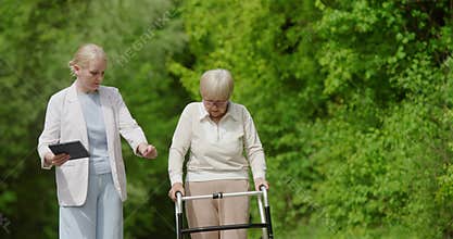 A caregiver is providing assistance to an elderly woman as they enjoy nature together
