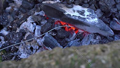 Glowing embers and ashes transforming in outdoor fire pit at twilight