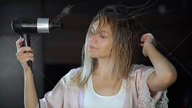 young beautiful woman dries and style your hair dryer at home in front of mirror