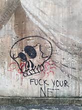 Graffiti of a stylized skull on a cement wall.