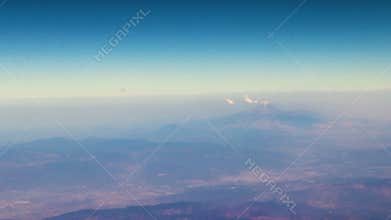 Flying airplane over Mexico clouds sky vlcanoes mountains desert landscape