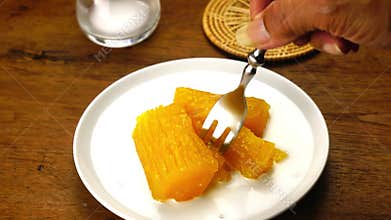 Eating cassava in syrup in white ceramic plate with coconut milk.