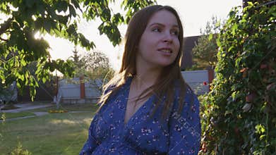 Beautiful pregnant woman enjoying fresh air at sunset rays on the backyard
