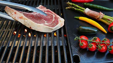 Beef steak with bone put on cast iron grill barbecue. Slow motion