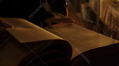 Man reading large mysterious book. Stock footage. Close-up of mysterious man reading ancient forbidden book in library